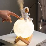 Kreative Astronautenlampe, die einen kleinen Astronauten im Raumanzug zeigt, der auf einer leuchtenden Mondlampe sitzt, ideal für Science-Fiction- und Weltraumliebhaber.