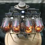 Vintage Vakuumröhre mit sichtbaren Elektronikkomponenten, leuchtend im Inneren, auf einer Holzbasis montiert, zeigt alte Technologie und Elektronikdesign.