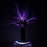 Elektrischer Plasma-Entladungsexperiment mit bläulichen Blitzen, die aus einer Kugel aufsteigen, auf einem dunklen Hintergrund.