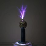 Eine Tesla-Spule erzeugt einen beeindruckenden Blitzeffekt mit bläulicher Elektrizität, die aus einer metallischen Kugel sprüht, auf einem dunklen Hintergrund.