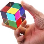 Hand hält einen bunten, reflektierenden Zauberwürfel mit verschiedenen Farben, der als wissenschaftliches Dekorationsobjekt dient.