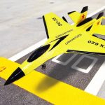 Modell eines gelben Jet-Kunstflugzeugs mit chinesischer Luftwaffenmarkierung, detailreich gestaltet, auf einer Startbahn liegend.
