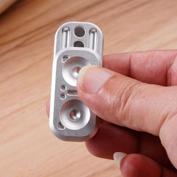 Nahaufnahme eines kleinen wissenschaftlichen Geräts, das in einer Hand gehalten wird, mit metallischer Oberfläche und mehreren runden Elementen.