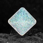 Holografisches Glasobjekt mit schimmernder, regenbogenartiger Oberfläche, schwebend auf einer dunklen Oberfläche.