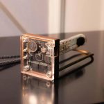 Wissenschaftliches Gerät mit transparentem Gehäuse, elektronischen Komponenten und Metallrahmen, ideal für Dekoration und wissenschaftliche Präsentationen.