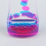 Bunter Blasentest mit farbigen Flüssigkeiten in einem transparenten Becher, zeigt chemische Reaktionen und Farbwechsel.
