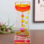 Farbige Flüssigkeit in einem transparenten, gewundenen Behälter, der an eine Quallenform erinnert, mit bunten Tropfen, die im Inneren schweben.