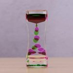 Transparentes Experimentierglas mit schwebenden, bunten Farbperlen, die durch die Schwerkraft nach unten sinken, ideal für wissenschaftliche Demonstrationen und Dekorationen.
