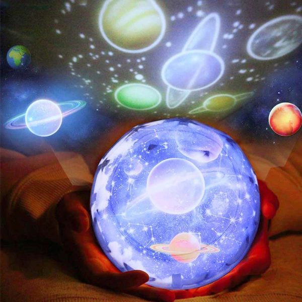 Hand hält leuchtende Planetenkugel mit schwebenden, leuchtenden Planeten und Sternen, die eine kosmische Szene in einem dunklen Raum darstellen.