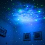 Laserprojektor, der einen Sternenhimmel an die Decke projiziert, mit blauen und grünen Lichtpunkten, ideal für Schlafzimmer oder Kinderzimmer.