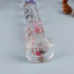 Transparente Glasröhre mit pinken Kristallen und Flüssigkeit, wissenschaftliches Dekor, ideal für Bildung und Experimente.