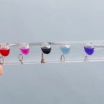 Mehrfarbige Flüssigkeitsperlen in Wasser, die an einer transparenten Schnur hängen, als wissenschaftliches Dekorations- oder Lehrmaterial.