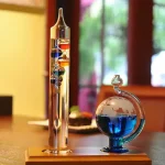 Zwei wissenschaftliche Glasgeräte, ein längliches mit bunten Kugeln und ein rundes mit blauer Flüssigkeit, auf einem Holztablett. Perfekt für Dekoration und wissenschaftliche Experimente.