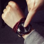Uhr mit Touch-Display, das durch Berührung aktiviert wird, kombiniert mit roten Perlenarmbändern, stilvolles Accessoire für Technik- und Modebegeisterte.