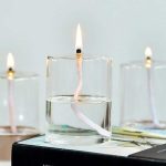 Wissenschaftliche Kerze mit brennender Flamme, die in einem Glas Wasser schwimmt, ideal für wissenschaftliche Dekorationen und Experimente.