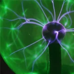 Nahaufnahme eines elektrischen Funkenentladungssatzes mit leuchtenden blauen und grünen Plasmaentladungen, die aus einer zentralen Kugel strahlen.