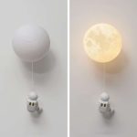 Dekorative Himmelslaterne in Mondform, beleuchtet, mit kleiner Astronautenfigur, ideal für Raumdekorationen und wissenschaftliche Themen.