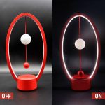 Modernes lichtschwebendes Pendel mit rot-weißer Kugel, das im Dunkeln leuchtet, zeigt physikalische Prinzipien der Schwerkraft und Magnetismus.