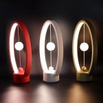Moderne Lichtspieluhr mit Pendel in Rot, Weiß und Gold, dekoratives und beruhigendes Design für Zuhause oder Büro.