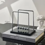 Elegante Newton-Wiege mit fünf Metallkugeln auf schwarzem Sockel, ideal für wissenschaftliche Dekorationen und Bildungszwecke.