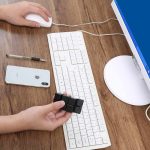 Wissenschaftliches Gadget auf einem Schreibtisch mit Computer, Tastatur, Maus, Smartphone und Schreibgerät, ideal für Technik- und Wissenschaftsbegeisterte.