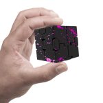 Hand hält ein kleines, schwarzes Raumfahrzeug-Modell mit pinken Spritzern, das auf Wissenschaft und Weltraumforschung hinweist.