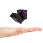 Ein handgehaltener Würfel mit schwarzen Flächen und pinken Farbklecksen, die dynamisch aus den Würfeln sprühen, symbolisiert wissenschaftliche Experimente und kreative Dekoration.