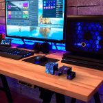 Moderner Computerarbeitsplatz mit wissenschaftlichen Gadgets, inklusive Würfel und Cube-Modelle, auf einem Holzschreibtisch mit LED-Beleuchtung.