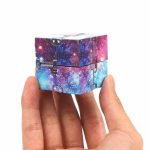 Hand hält einen kleinen Würfel mit Galaxy-Motiv, der aus mehreren Teilen besteht, die zusammen ein Sternenbild im Weltraum darstellen. Perfekt für Wissenschafts- und Dekorationsliebhaber.