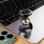 Modernes wissenschaftliches Gadget mit Metallring und Smartphone auf einem Laptop, ideal für Technik- und Wissenschaftsbegeisterte.