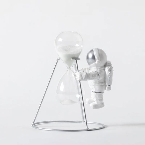 Raumfahrer-Statue neben einer Sanduhr auf einem weißen Hintergrund, dekoratives wissenschaftliches Element.