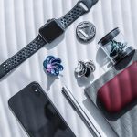 Moderne Smartwatch mit austauschbaren Armbändern, Kopfhörern, USB-Stick, Smartphone und weiteren technischen Accessoires auf weißem Hintergrund.