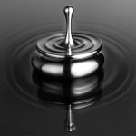 Nahaufnahme eines Wassersteins, der eine Wasserperle bildet, mit reflektierenden Oberflächen und ruhigem Wasser im Hintergrund.