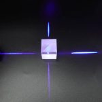 Ein kleines, transparentes Quader-Objekt, das von blauen Laserstrahlen beleuchtet wird, zeigt ein faszinierendes physikalisches Phänomen.