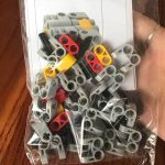 Packung mit bunten Steckbausteinen in Grau, Rot, Gelb und Schwarz, ideal für wissenschaftliche Experimente und kreative Bauprojekte.
