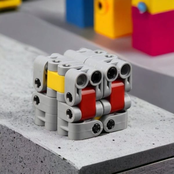 Kreativer Roboter aus LEGO-Steinen, gebaut mit bunten Bausteinen in Grau, Rot, Gelb und Blau, auf einer grauen Oberfläche.