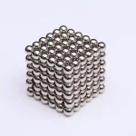 Ein 3D-Würfel aus kleinen, glänzenden Metallkugeln, der wissenschaftliche Prinzipien und magnetische Eigenschaften zeigt.