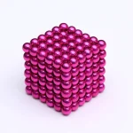 Ein 3D-Modell eines magnetischen Würfels, bestehend aus glänzenden, pinkfarbenen Kugeln, die aneinander haften und eine geometrische Form bilden.