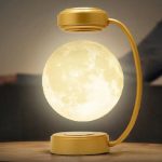 Kreative Tischlampe in Mondform mit goldfarbenem Lampenschirm und flexiblem Arm, ideal als dekoratives Lichtstück für moderne Wohnräume.