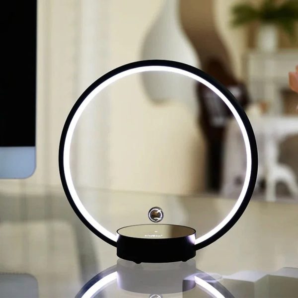 Modernes Lichtdekor mit kreisförmigem LED-Licht und schwebender Glaskugel auf einem weißen Tisch, ideal für stilvolle Raumgestaltung.