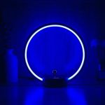 Neon-Ring in blauer Farbe, leuchtend in dunklem Raum, dekoratives wissenschaftliches Lichtobjekt.