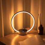 Moderne Kerzenlicht-Ringlampe mit Aromadiffusor auf einem Holzschreibtisch, schafft eine gemütliche Atmosphäre.