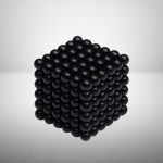 Dreidimensionaler Würfel aus schwarzen Kugeln, die präzise angeordnet sind, um eine geometrische Form zu bilden.