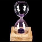 Elegante Sanduhr mit Lavendel im Glas, auf einem Holzsockel, ideal für wissenschaftliche Dekorationen und stilvolle Raumgestaltung.