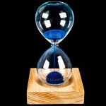 Elegante Sanduhr mit blauer Sandfüllung auf Holzsockel, ideal für wissenschaftliche Dekorationen und moderne Raumgestaltung.