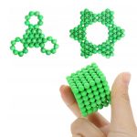 Grüne magnetische Kugeln, die zu einer Triskel-Form, einer Sternform und einem Würfel zusammengesetzt sind, auf weißem Hintergrund.