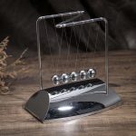 Elegante Newton-Wiege aus Metall auf Holzoberfläche, ideal für wissenschaftliche Dekorationen und Lernzwecke.
