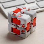 Modernes 3D-Puzzle Würfel mit weißen und roten Teilen, ideal für Denksport und Gehirntraining, auf einem Schreibtisch mit Tastatur im Hintergrund.