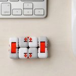 Modernes Schiebepuzzle mit weißen Würfeln und roten Elementen, auf einem Schreibtisch neben einer Tastatur. Perfekt für Wissenschafts- und Dekorationsliebhaber.