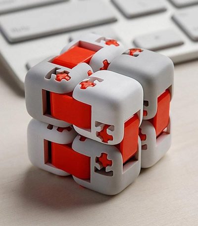 Modernes 3D-Puzzle Würfel mit weißen und roten Teilen, ideal für Denksport und Gehirntraining, auf einem Schreibtisch mit Tastatur im Hintergrund.